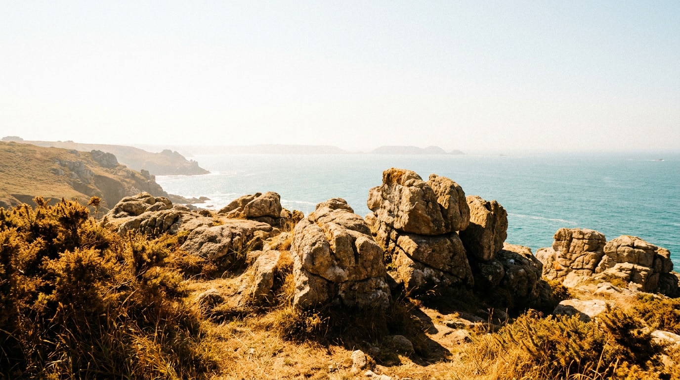 Falaises rocheuses surplombant une mer azur sous un soleil éclatant lors d'un épisode de canicule en Bretagne.